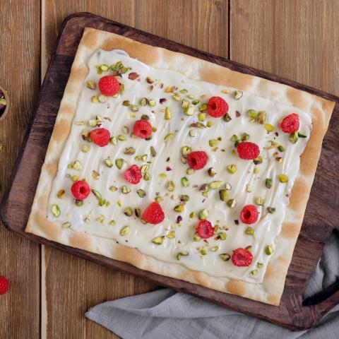 Dessertpizza aus weisser Schokolade mit Himbeeren und Pistazien